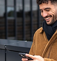 Junger Mann mit Handy in der Hand - mhplus Newsletter