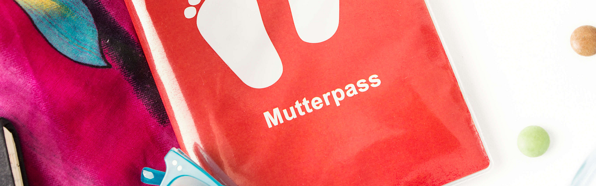 Ein Mutterpass liegt neben anderem Kleinkram auf einem Tisch