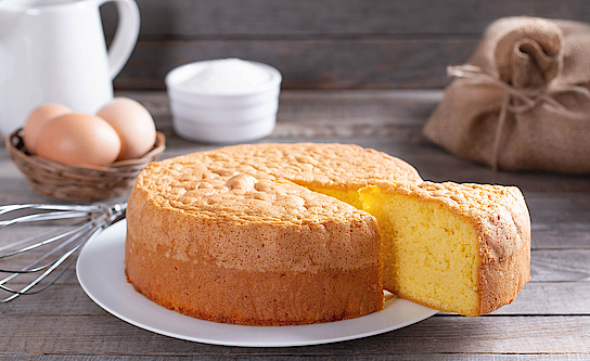 Auf einem Tisch steht ein Kuchen. Ein Stück ist aufgeschnitten. 