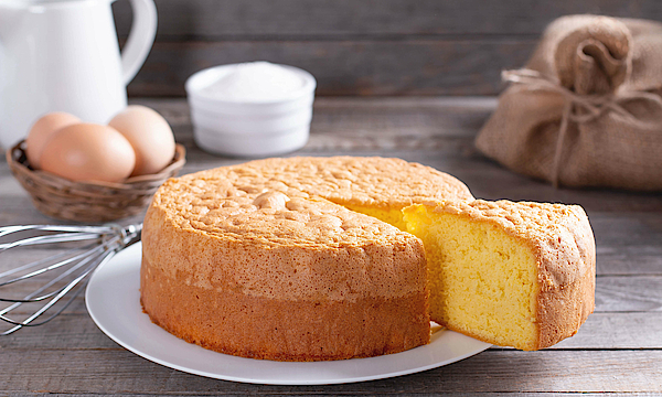 Auf einem Tisch steht ein Kuchen. Ein Stück ist aufgeschnitten. 