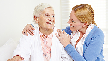 Lachende Seniorin schaut ihre Tochter an.