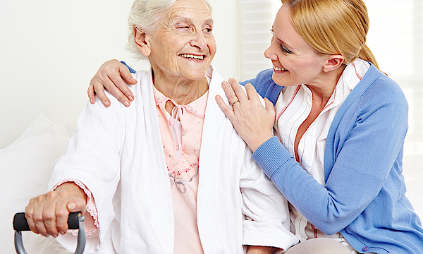 Lachende Seniorin schaut ihre Tochter an.