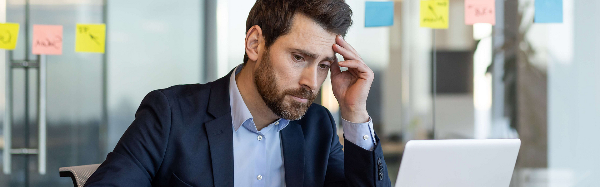 Mann vor einem Laptop sucht nach Methoden für den Umgang mit Stress am Arbeitsplatz