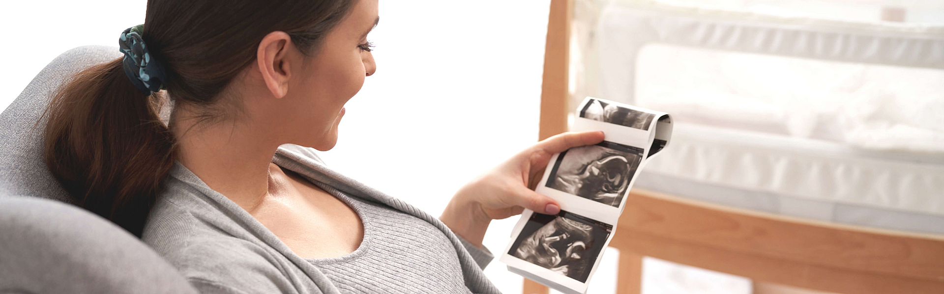 Schwangere Frau schaut das Ultraschallbild des ungeborenen Babys an.