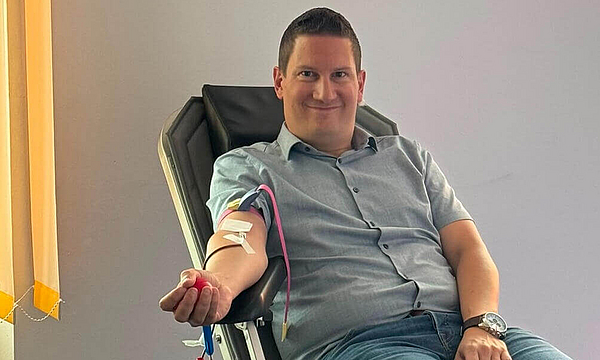 mhplus-Geschäftsstellenleiter Daniel Strötz sitzt auf einer Liege und macht eine Blutspende