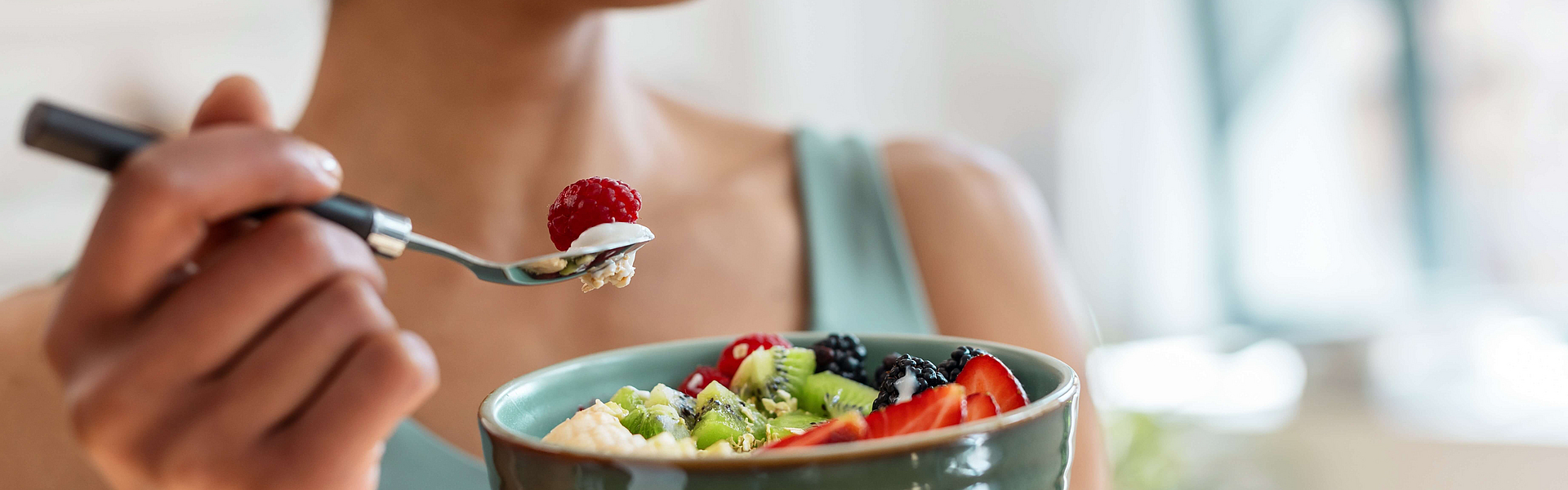 Junge Frau hält eine Müslischalte mit Obst für entzündungshemmende Ernährung