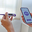 Nahaufnahme von Händen einer Frau, die ein Basalthermometer und Smartphone halten, dass die Basaltemperatur anzeigt.