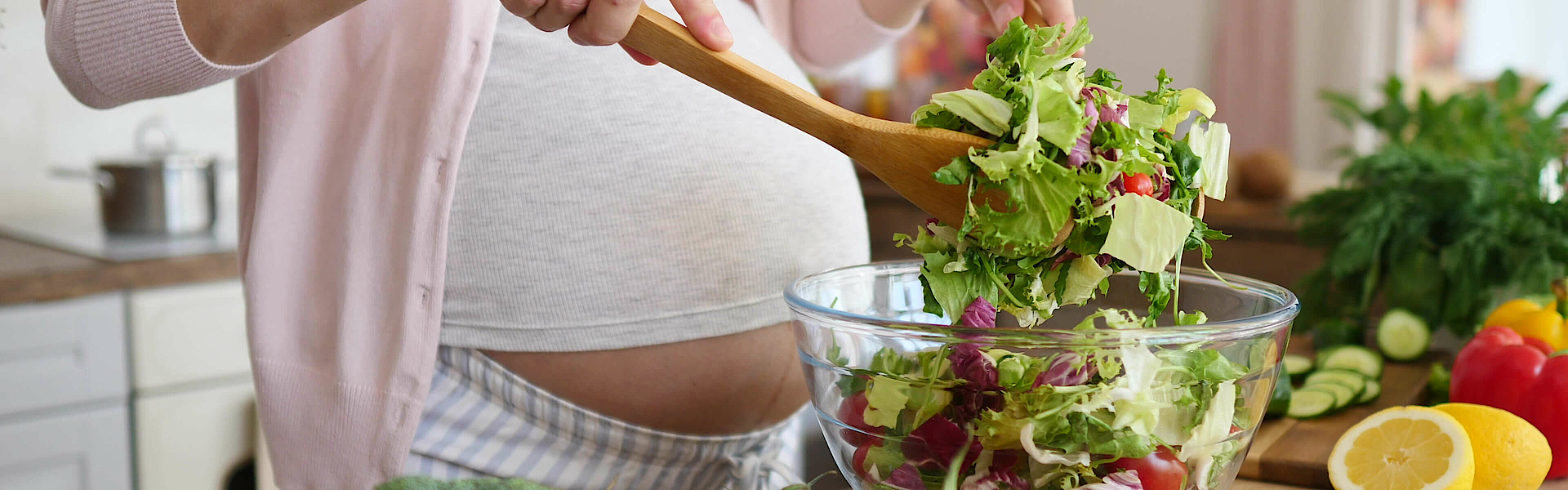 Schwangere Frau bereitet Salat vor.