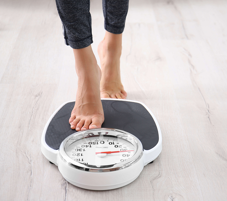 Eine Frau tritt auf eine Körperwaage.