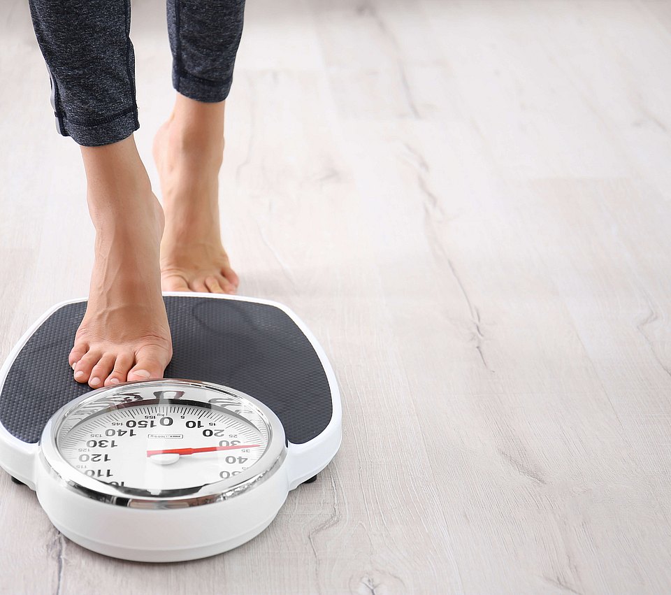 Eine Frau tritt auf eine Körperwaage.