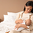 Frau sitzt im Bett und stillt ein Baby. 