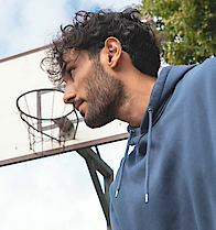 Mann prellt auf dem Sportplatz einen Basketball.