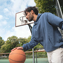 Mann prellt auf dem Sportplatz einen Basketball.