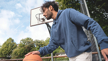 Mann mit Basketball, nimmt an den Bonusprogrammen teil.