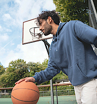 Mann prellt auf dem Sportplatz einen Basketball.