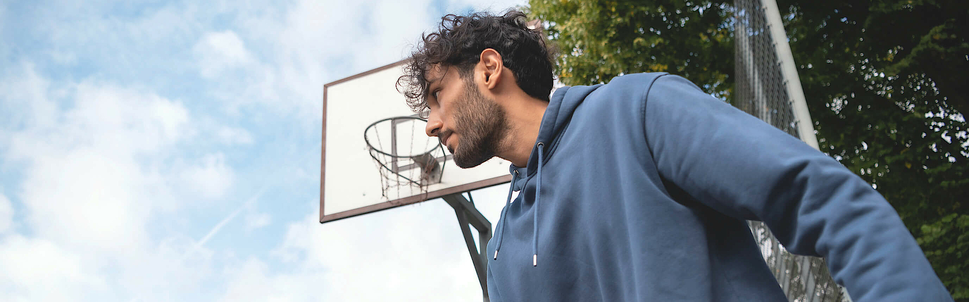 Mann prellt auf dem Sportplatz einen Basketball.