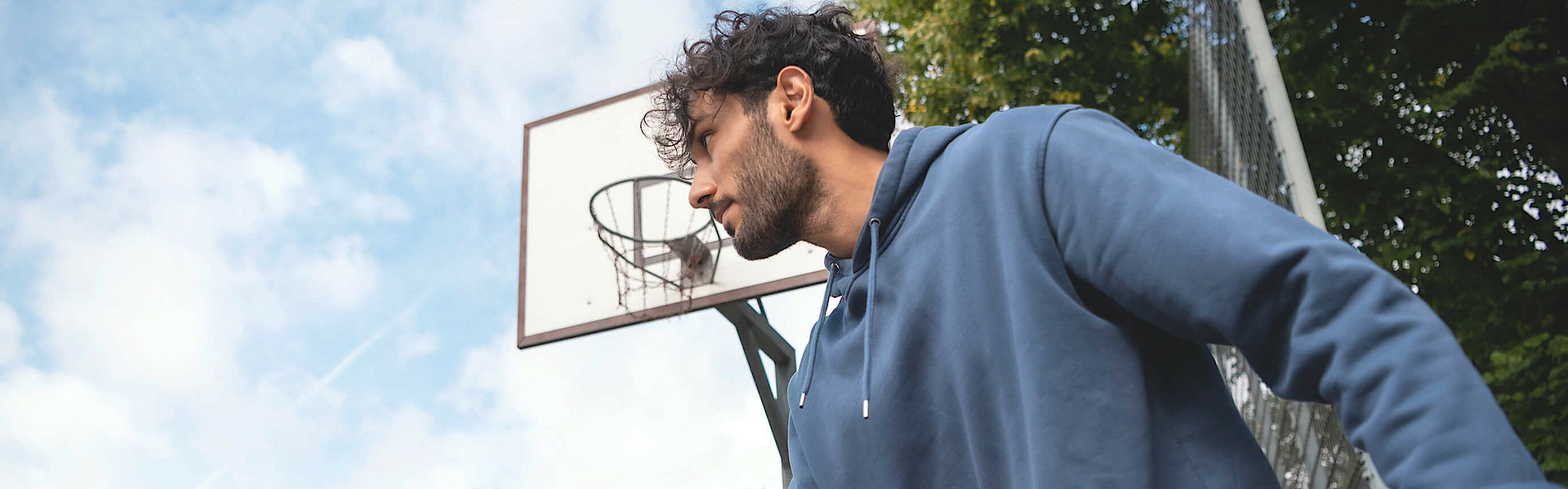 Mann prellt auf dem Sportplatz einen Basketball.