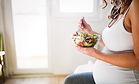 Eine schwangere Frau isst einen Salat