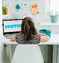 Ein Mädchen sitzt an einem Schreibtisch vor einem Laptop und schaut Pfiffix-TV.
