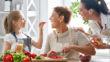Zu sehen ist eine Familie die glücklich Zeit in der Küche verbringt