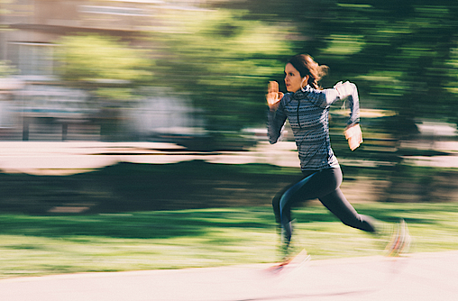 Frau joggt sehr schnell im Wald, sie macht Intervalltraining