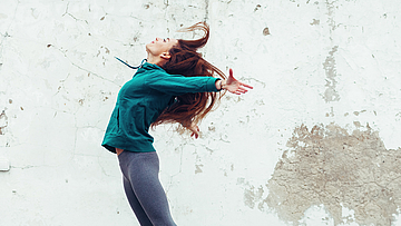 Eine junge Frau in sportlicher Kleidung springt in die Luft.