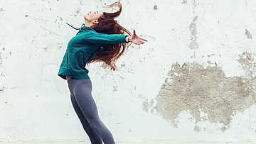 Eine junge Frau in sportlicher Kleidung springt in die Luft.