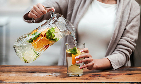 Frau füllt Glas mit Detoxwasser.