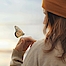 Eine Frau hält einen Schmetterling in der Hand. Sie schaut entspannt auf diesen Schmetterling.
