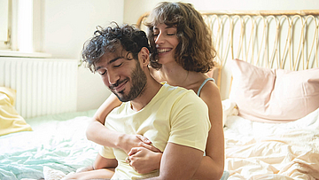 Glückliches Paar sitzt zusammen auf dem Bett.