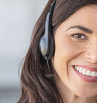 Eine Agentin in eine Callcenter mit einem Headset. Sie lacht.