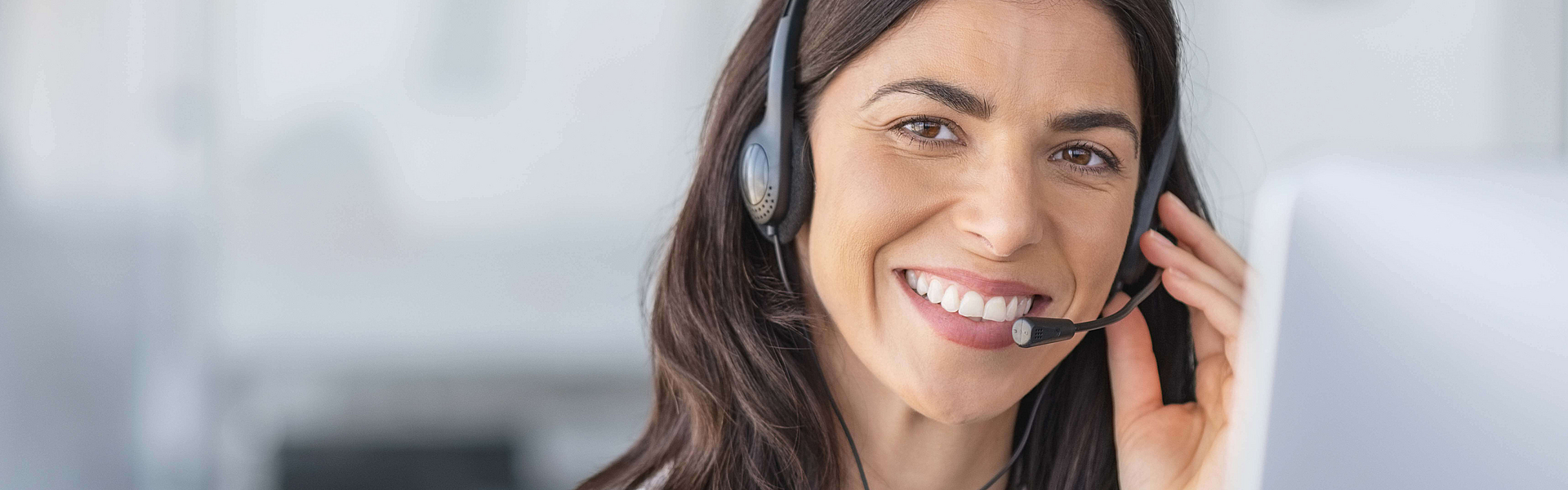 Eine Agentin in eine Callcenter mit einem Headset. Sie lacht.