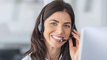 Eine Agentin in eine Callcenter mit einem Headset. Sie lacht.