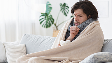 Ein kranker Mann sitzt auf dem Sofa - er bezieht Krankengeld.