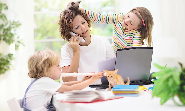 Eine Mutter arbeitet im Homeoffice. Die Tochter spielt mit einem Dinosaurier auf ihrem Kopf. Der Junge spielt Blockflöte. Die Mutter ist genervt, denn sie telefoniert.