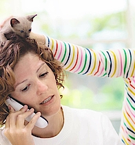 Eine Mutter arbeitet im Homeoffice. Die Tochter spielt mit einem Dinosaurier auf ihrem Kopf. Der Junge spielt Blockflöte. Die Mutter ist genervt, denn sie telefoniert.