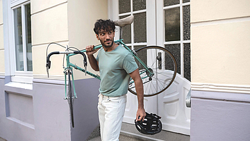 Ein Mann trägt ein Fahrrad auf den Schultern.