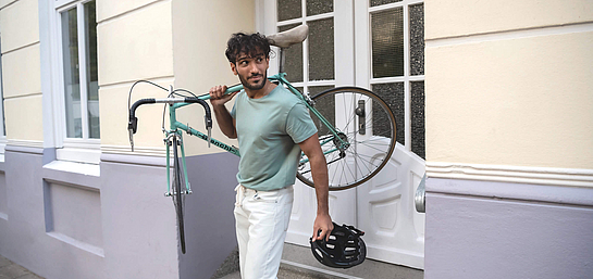 Ein Mann trägt ein Fahrrad auf den Schultern.