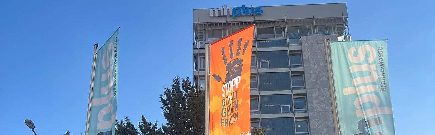 Flagge zu Orange The World weht vor mhplus-Hochhaus in Ludwigsburg neben einer Unternehmensflagge