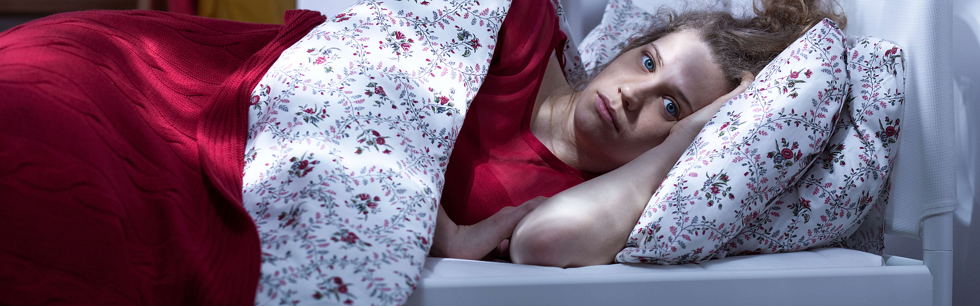 Frau im Bett, ist wach, leidet unter Einschlafstörungen oder Durchschlafstörungen