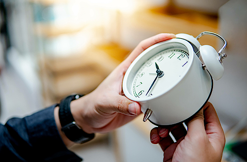 Männliche Hand, die die Zeit auf der weißen Uhr justiert oder ändert. Zeitmanagement-Konzept.