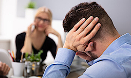 Ein Business-Mann hält sich die Ohren zu. Er fühlt sich von den Telefonaten seiner Partnerin gestört.