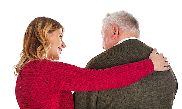 Frau und älterer Mann stehen mit dem Rücken zum Bild. Die Frau umarmt den Mann.