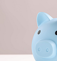 Hand steckt Kleingeld in blaues Sparschwein