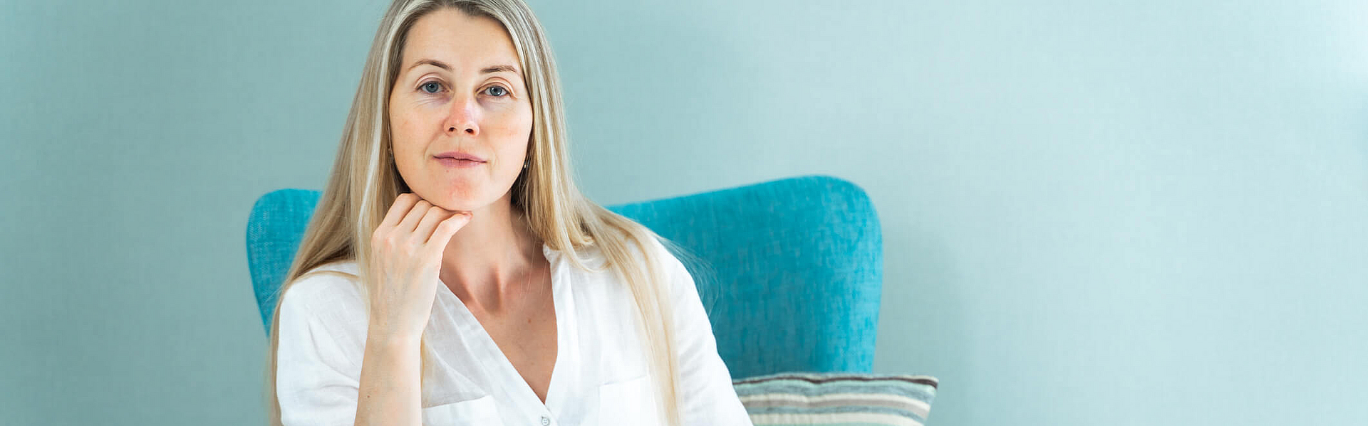 Frau im mittleren Alter sitzt in einem blauen Sessel