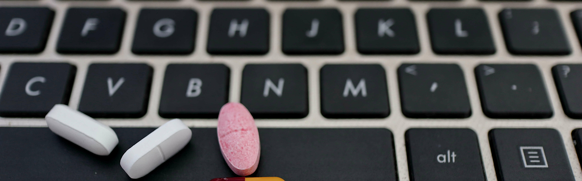 verschiedene Arten von Drogen, die auf einem Laptop-Tastatur, ein Symbol der Technologie kranken Menschen