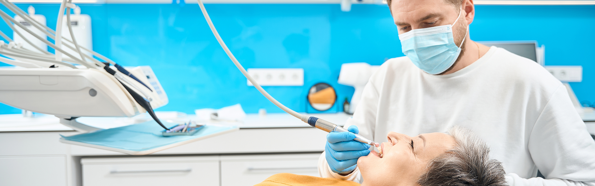 Eine Frau liegt auf der Liege einer Zahnarztpraxis und lässt eine professionelle Zahnreinigung durchführen.