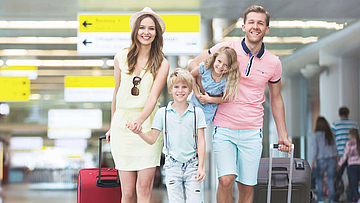 Am Flughafen, eine Familie mit Koffern ist auf dem Weg zum Abfluggate.