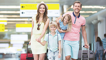 Am Flughafen, eine Familie mit Koffern ist auf dem Weg zum Abfluggate.