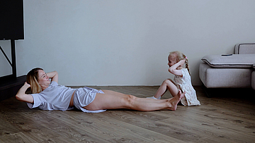 Mutter und kleine Tochter machen Gymnastik auf dem Fußboden